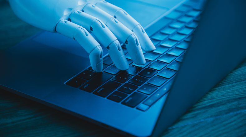 Robotic hand on laptop keyboard to depict cybersecurity.